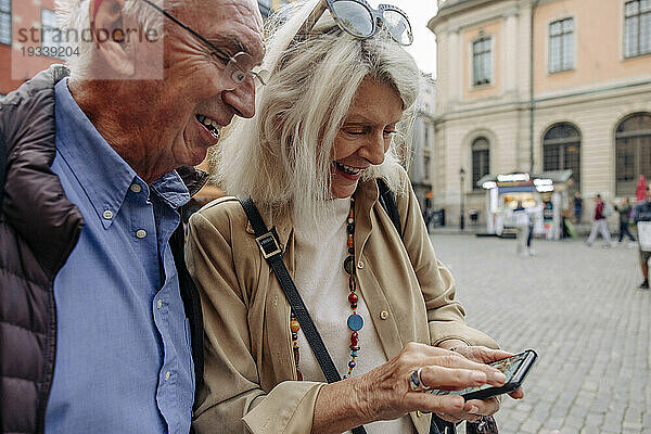 Glückliches älteres Paar  das sein Smartphone teilt  während es die Stadt erkundet