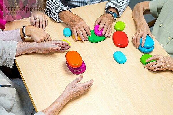 Draufsicht auf die Hände von alten Menschen  die in einem Pflegeheim ein Brettspiel spielen