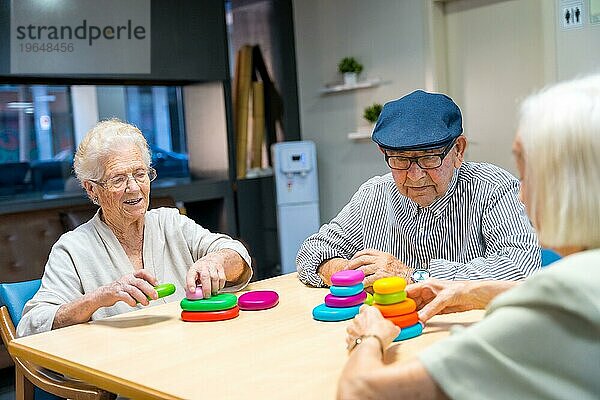 Drei niedliche ältere Menschen  die zusammen in einem Pflegeheim Geschicklichkeitsspiele spielen