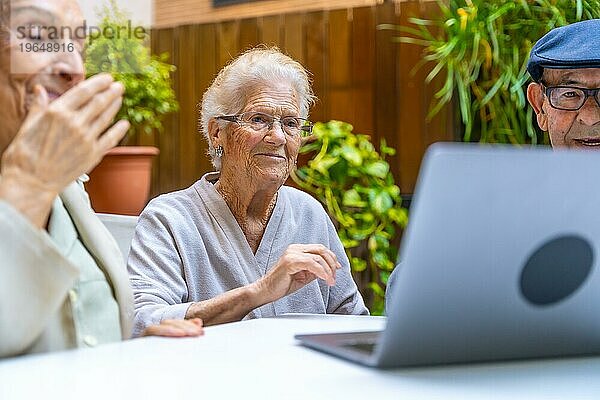 Niedliche ältere Menschen  die in einer geriatrischen Einrichtung lernen  wie man einen Laptop benutzt