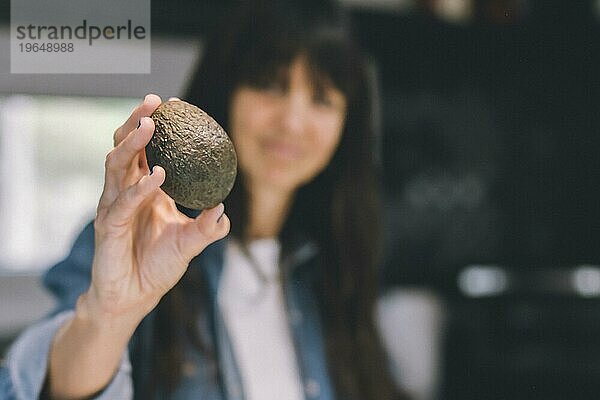 Frau zeigt eine Avocado. Raum kopieren