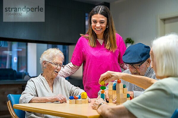 Krankenschwester und ältere Menschen spielen Geschicklichkeitsspiele in einem Pflegeheim