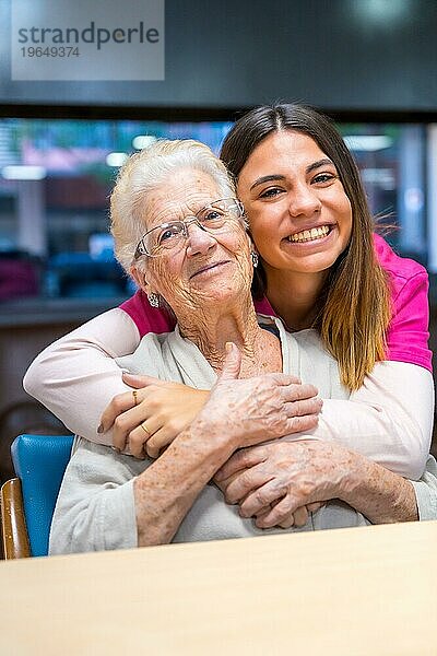 Vertikales Porträt einer netten Krankenschwester und einer älteren Frau in einer geriatrischen