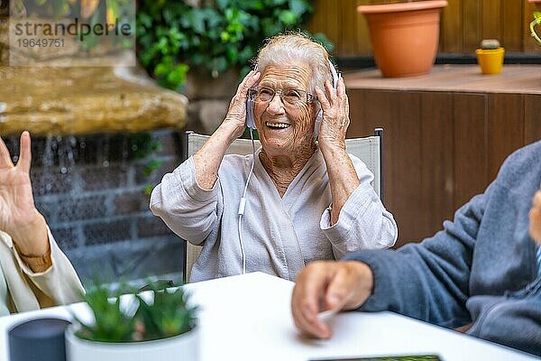 Glückliche Senioren mit Kopfhörern und viel Spaß in einem Pflegeheim