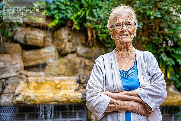Lächelnde ältere Frau  die in die Kamera schaut und lächelt  im Garten eines Pflegeheims