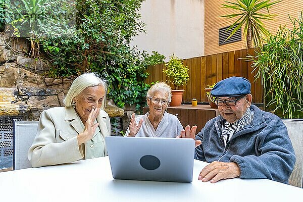 Einführung in die Technologie für ältere Menschen in einem Pflegeheim  während drei Personen einen Laptop benutzen
