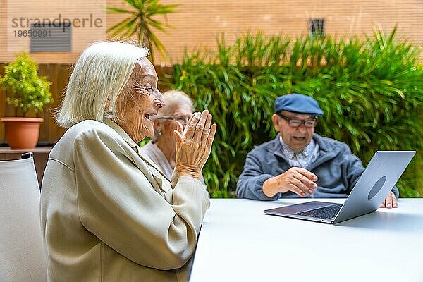 Ältere Menschen lächeln und haben Spaß bei der Benutzung eines Laptops in einer geriatrischen Einrichtung