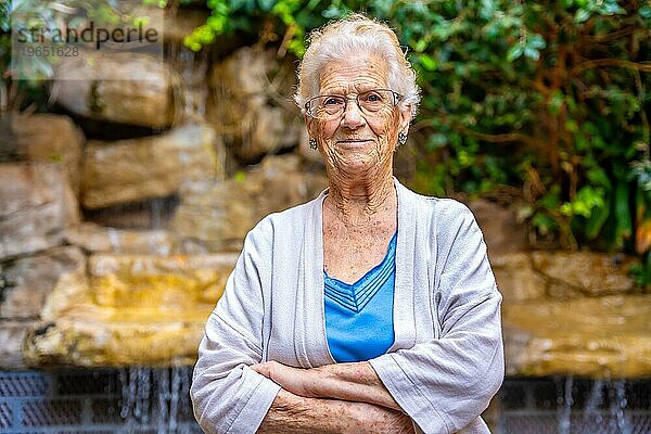 Stolze ältere Frau schaut in die Kamera im Garten eines Pflegeheims