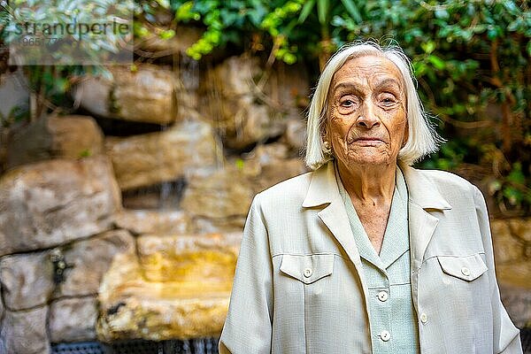 Porträt einer älteren Frau im Garten eines Pflegeheims