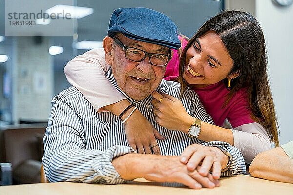 Zärtlicher Moment einer Krankenschwester  die einen älteren Mann in einer geriatrischen Einrichtung umarmt