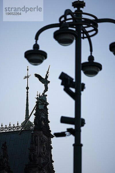 Engelsfigur mit Schwert auf dem Dach vom Rathaus kämpft gegen einen Mast mit Lampen und Videokameras  Überwachungskameras  Rathausmarkt  Hamburg  Deutschland  Europa