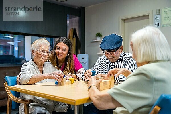 Ältere Menschen und eine Krankenschwester in einem Pflegeheim tauschen sich über Geschicklichkeitsspiele aus