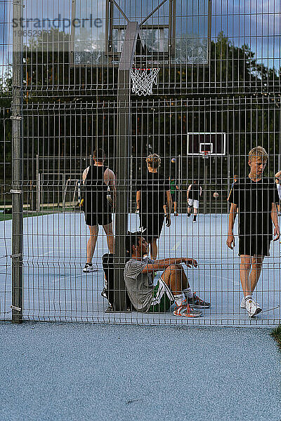 Männer spielen Basketball auf einem offenen Platz.