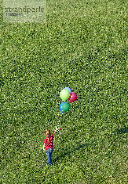 Ein junges Mädchen mit Luftballons steht allein auf einem Feld  Durham  Connecticut.