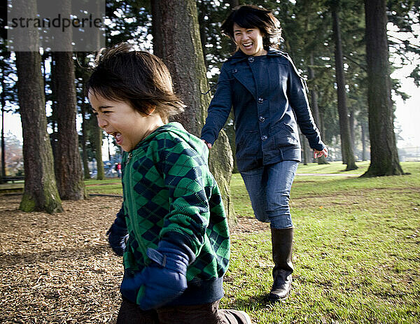 Ein Junge lacht  während er durch einen Park rennt.