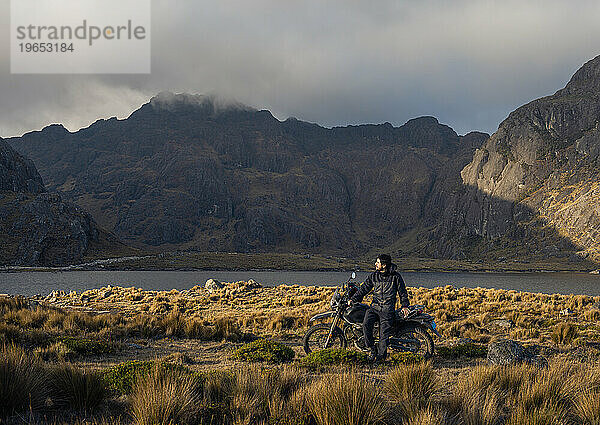 Abenteuer-Motorradfahrer auf Berg und See von Peru bei Sonnenuntergang