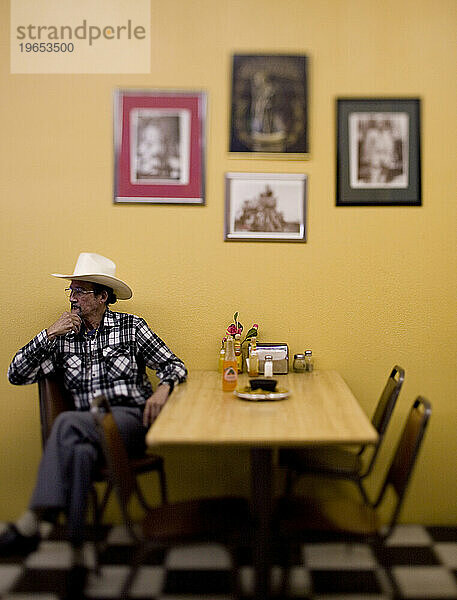 Ein Porträt eines lateinamerikanischen Mannes und seines Cowboyhutes in einem Restaurant.