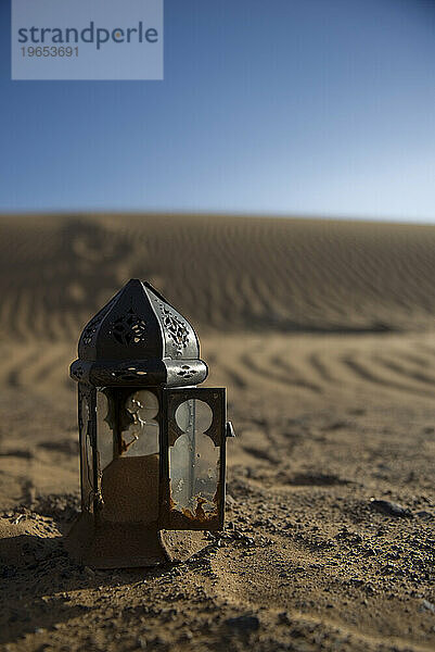 Eine kaputte Lampe sammelt Sand in der Wüste.