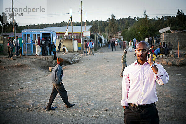 Ein junger äthiopischer Mann telefoniert auf einer staubigen Straße in Äthiopien.