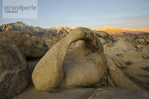 Die östliche Sierra Nevada wird bei Sonnenaufgang beleuchtet  mit dem Mobius Arch im Vordergrund in den Alabama Hills  Kalifornien.