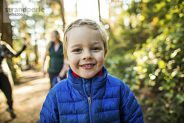 Porträt eines jungen  glücklichen Kindes in blauer Jacke im Freien