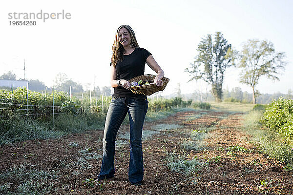 Ein junges Mädchen hält einen Korb mit Gemüse auf einem Biobauernhof außerhalb von Atlanta  GA.