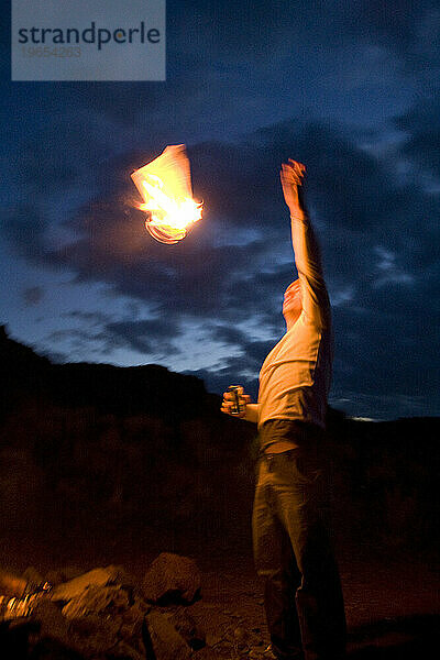 Ein Mann wirft ein Stück brennendes Papier in die Luft.
