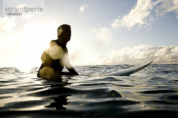 eine Silhouette eines Surfers  der auf seinem Brett sitzt