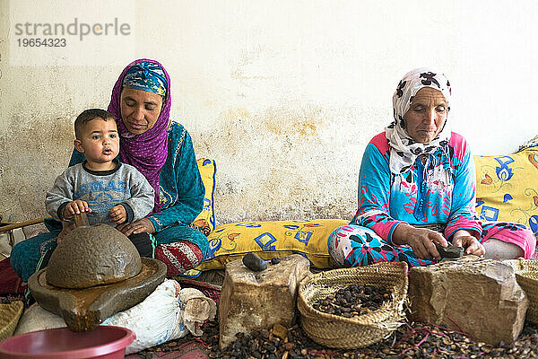 Zwei Berberfrauen in traditioneller Kleidung extrahieren Arganöl aus den Kernen des Arganbaums