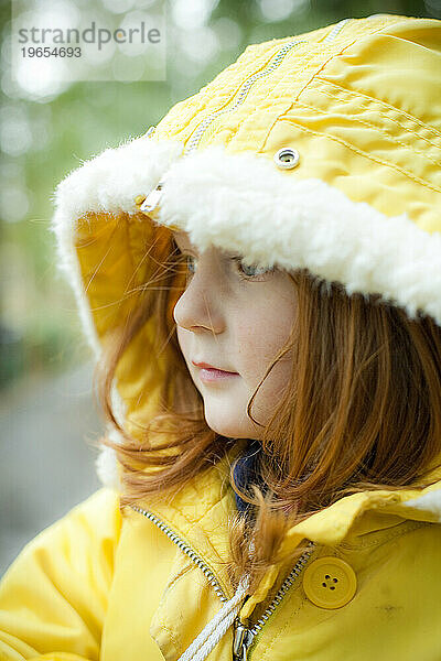 Ein rothaariges Mädchen  das sich für das kalte Wetter warm angezogen hat.