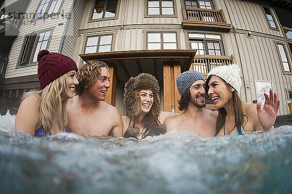 Gruppe von Freunden in einem Whirlpool im Winter.