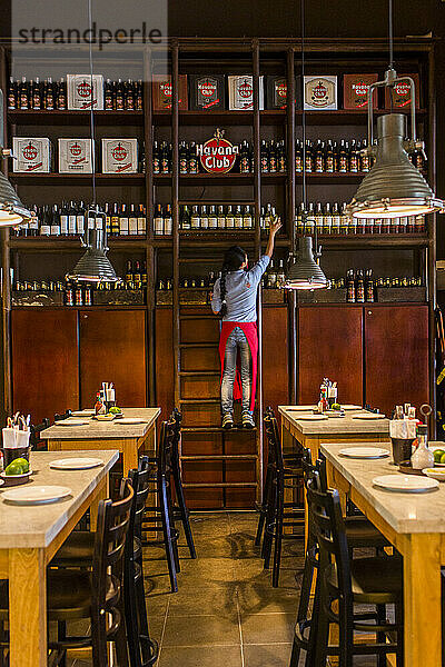 Woman pulling down bottle of rum at Central de Cevicheria  restaurant in Bogota  Colombia