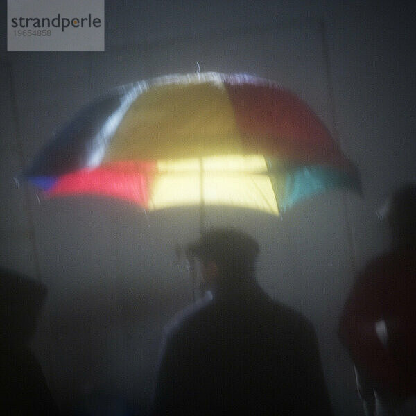 Silhouette einer Person unter einem Regenschirm in der Nacht.