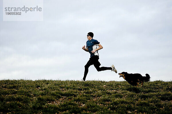 Ein Mann und sein Hund laufen über einen grasbewachsenen Hügel in der Nähe von Corvallis  Oregon.