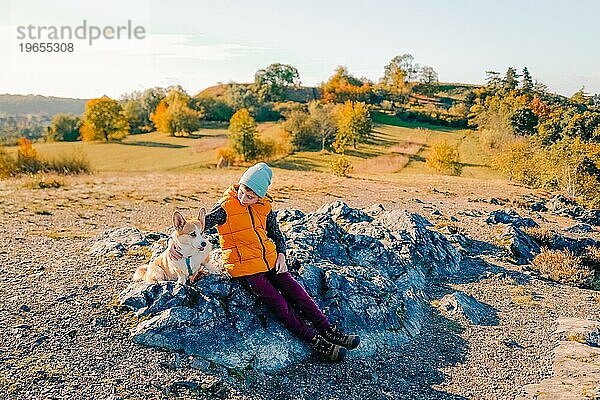 Ein Junge geht mit einem Corgi-Hund im Herbstwald spazieren