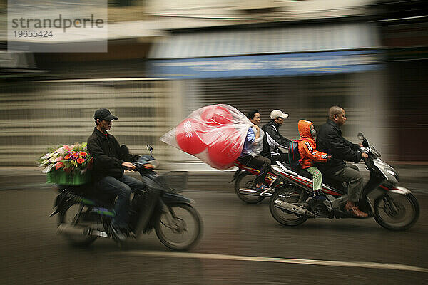 Drei Motorroller surren eine Straße in der „Altstadt“ von Hanoi entlang. (Bewegungsunschärfe)