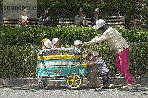 Eine Frau schiebt in Himeji  Japan  einen Kinderwagen mit sechs Kindern darin.