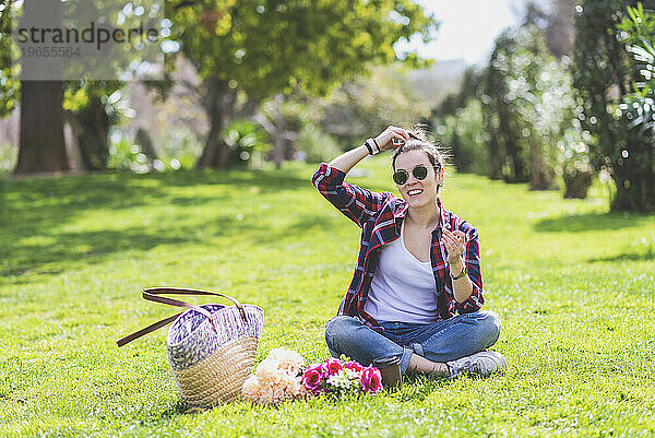 Vorderansicht einer jungen Hipster-Frau  die auf Gras in einem Park sitzt