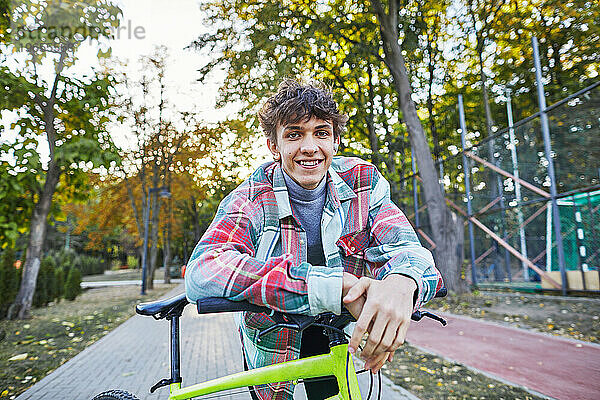 Lächelnder Teenager mit einem Fahrrad im Park