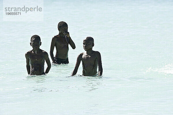 Drei einheimische Jungen waten im klaren Wasser der Turks- und Caicosinseln.