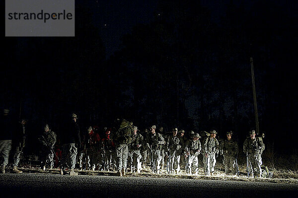 Soldaten stehen mitten in der Nacht während einer Feldübung in der Nähe einer unbefestigten Straße.