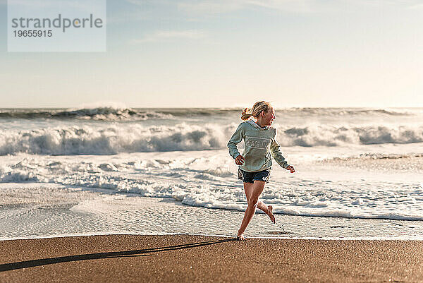 Mädchen lacht und rennt am Strand in Neuseeland