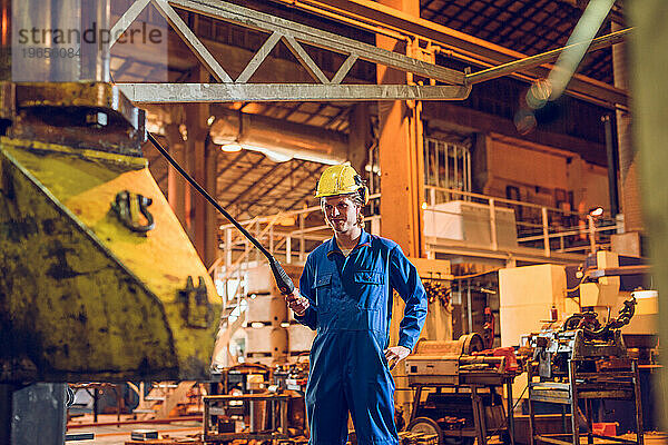 Lächelnder Mann  der an der Fabrik arbeitet