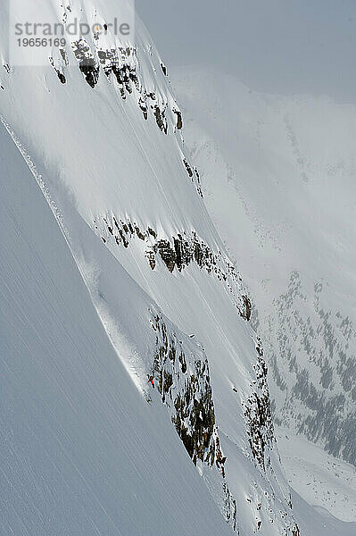 Ein einsamer Snowboarder  der sich schnell durch steiles Gelände bewegt.