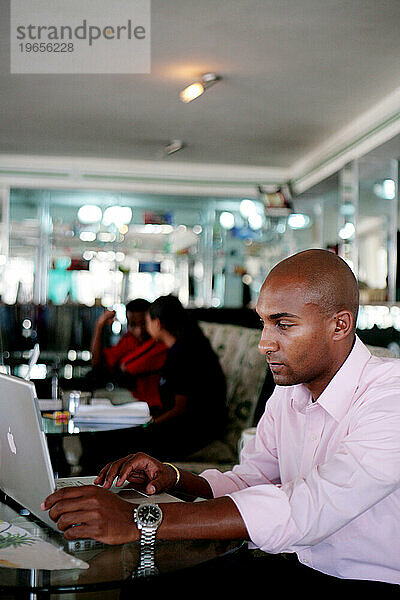 Ein junger äthiopischer Geschäftsmann arbeitet an seinem Laptop  während er in einem Café in Addis Abeba  Äthiopien  sitzt.