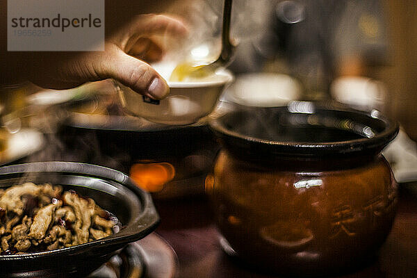 Chinesische Suppe in eine Schüssel gießen