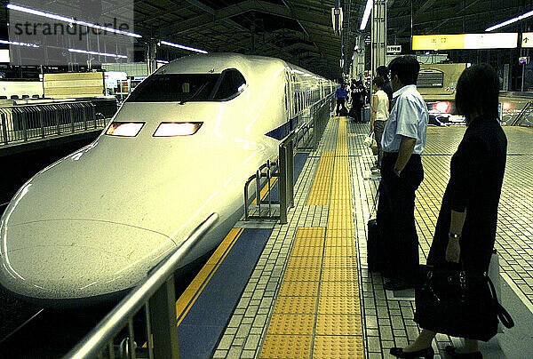 Mehrere Menschen warten darauf  in einem Bahnhof in Tokio  Japan  in den 200 Meilen pro Stunde schnellen Shinkansen oder „Hochgeschwindigkeitszug“ einzusteigen.