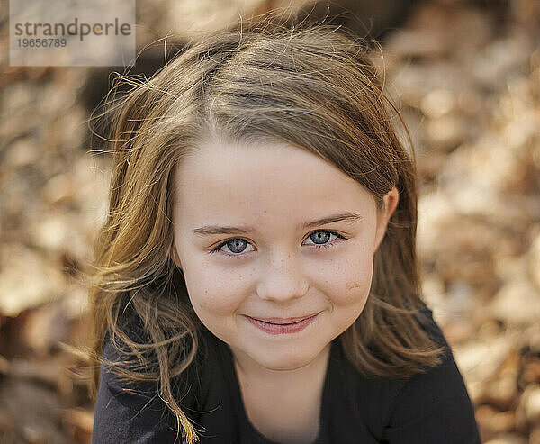 Glückliches kleines Mädchen  das im Herbst draußen lächelt