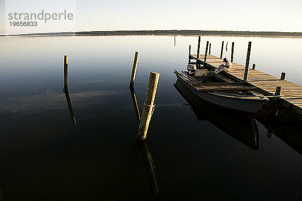 Ein Mann sitzt bei Sonnenuntergang nach einem Tag voller Austern in Apalachicola  Florida  ruhig auf dem Dock.