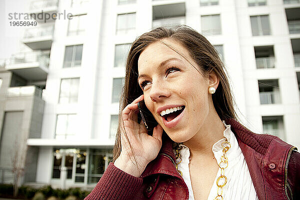 Eine Frau lächelt und lacht  während sie mit ihrem Handy spricht.